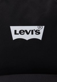 Black canvas background featuring a white Levi's logo in a curved shield shape, with bold, uppercase lettering.