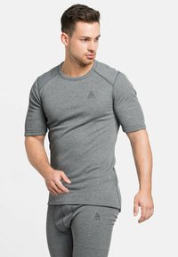 T-shirt de sport gris à manches courtes, doté d'un col rond et d'un logo sur la poitrine. Fabriqué en tissu doux et extensible.