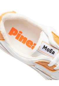 White sneaker with orange accents, textured furry lining, and a rectangular label reading "MoEa." The insole features the word "Pine!" in orange.