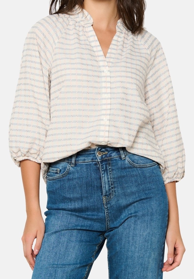 Lätt, mönstrad blus med knäppning fram, mandarin-krage och ballongärmar. Färgen har mjuk beige med blå och rosa ränder.