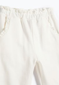 Pantalones de algodón blancos con una cinturilla elástica con volantes y bolsillos laterales, con una textura suave y un acabado liso.