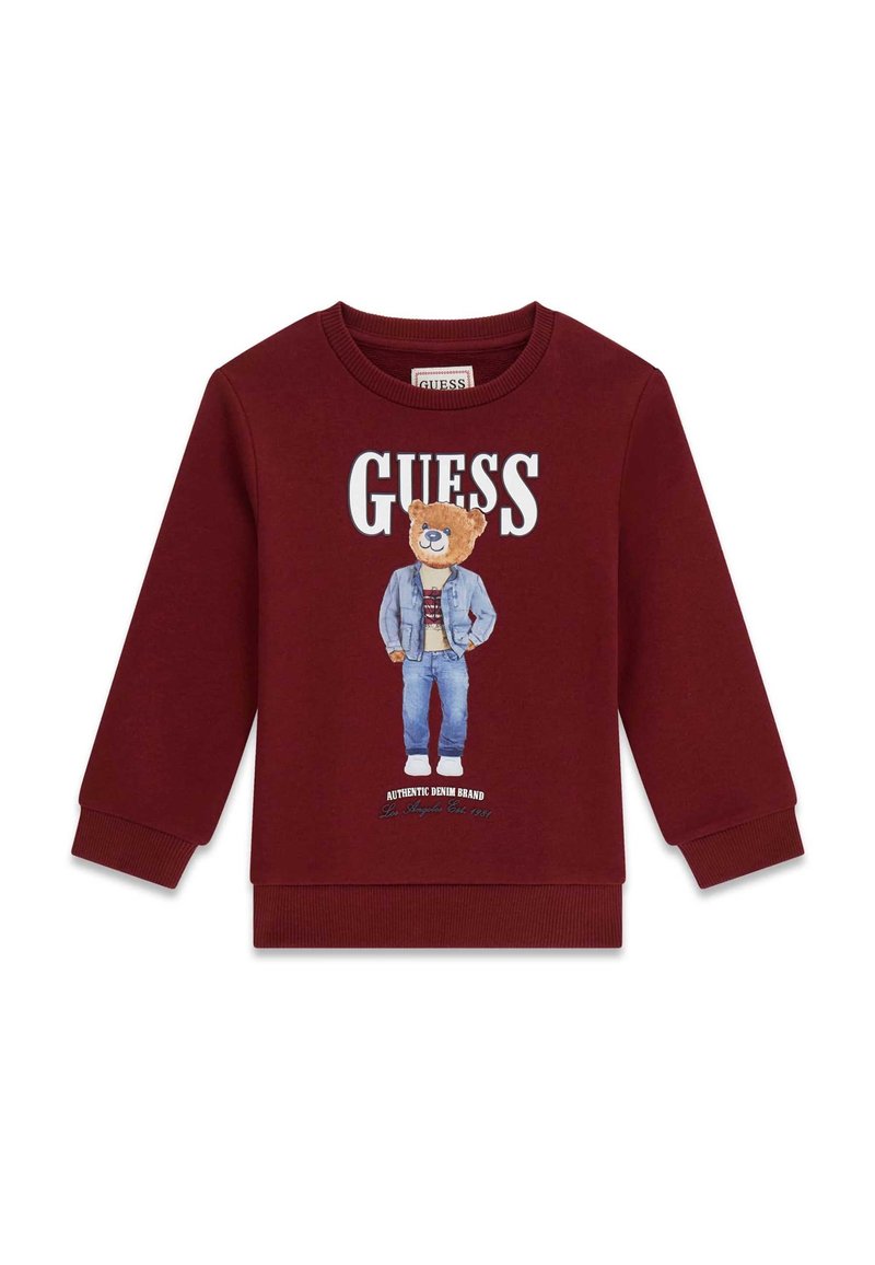 Sweat-shirt bordeaux avec un motif d'ours en tenue en jean. Logo "GUESS" au-dessus, poignets côtelés et texture de tissu douce.