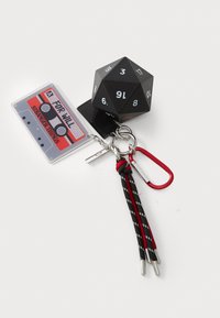 Atslēgu piekariņš ar melnu 20-sānu kauliņu ar baltām ciparu, kas veidots kā kasetes lente sarkanas un pelēkas krāsas, un melnas un sarkanas auklas akcentiem ar sudrabotu karabīni.