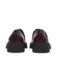 Scarpe in pelle color mogano con una finitura lucida, dotate di punta arrotondata, suola piatta nera bassa e dettagli di cucitura minimi sul retro.