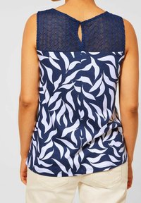 Marinblå tanktop med vitt lövmönster; strukturerad marinblå baksida med nyckelhålsdetalj; avslappnad passform; slät bomullstyg.