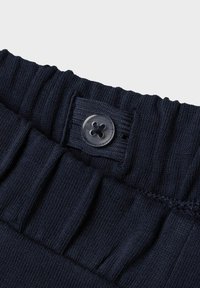Fascia in tessuto a coste di colore blu navy con un design elastico e un bottone trasparente con motivo a croce.