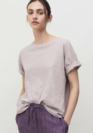 T-shirt grigio chiaro a maniche corte con orli arrotolati, realizzata in tessuto morbido, abbinata a pantaloni larghi di un viola scuro e dalla vestibilità comoda.