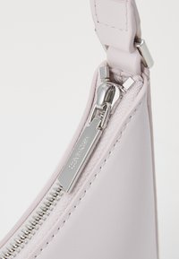 Light pink faux leather bag corner with silver zipper and pull. Hardware visible; zipper partially open, revealing lining.