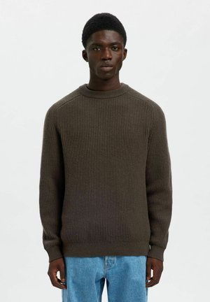 Maglione a coste di colore marrone scuro con collo rotondo e maniche lunghe, abbinato a jeans blu. Design semplice e tessuto dal texture lavorata.