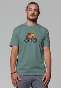 Groene katoenen t-shirt met een cartoonontwerp van een fietsende dier. Het dier draagt een helm en de fiets heeft zwarte wielen.