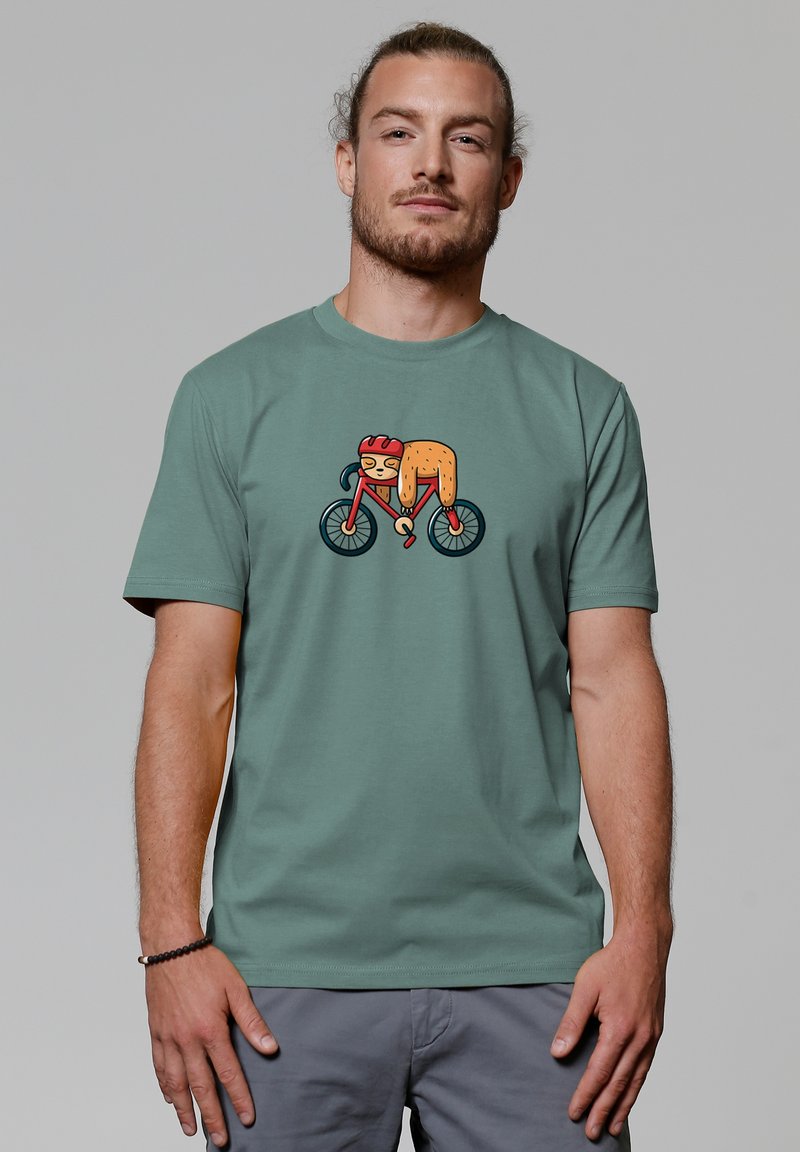 Groene katoenen t-shirt met een cartoonontwerp van een fietsende dier. Het dier draagt een helm en de fiets heeft zwarte wielen.