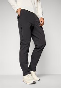 Zwarte sportbroek van zacht, rekbaar materiaal met een taps toelopend ontwerp, voorzien van een ritszak aan de zijkant en een comfortabele tailleband.
