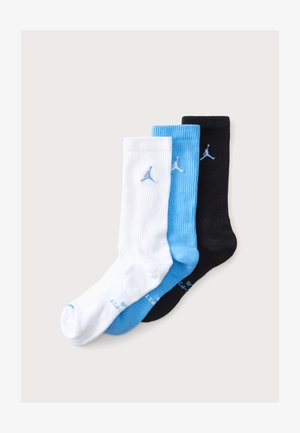 Trois paires de chaussettes montantes côtelées en blanc, bleu clair et noir avec un logo Jumpman bleu près du haut au centre de chaque chaussette.