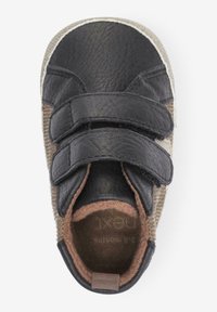 Zwarte leren schoen met twee klittenbandsluitingen, met een textiellichaam van bruin stof en een zachte binnenvoering. Ronde neus ontwerp.