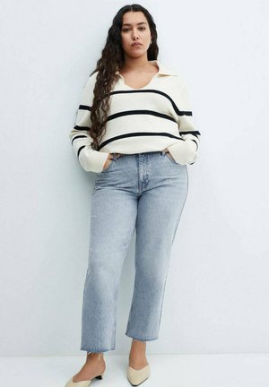 Hvid sweater med sorte striber, krave og lange ærmer; parret med lysblå lige ben jeans. Beige blokhælede sko.