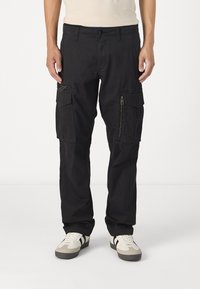 Sorte cargo bukser lavet af slidstærkt stof med flere sidelommer, lynlåsdetaljer og et lige ben design. Bæres med lette sneakers.
