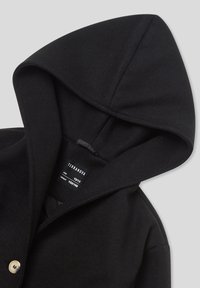 Cappotto nero con cappuccio, chiusura a bottoni e etichetta interna che mostra il marchio "Terranova", taglia 12/13 anni, altezza 152/158 cm su uno sfondo grigio.