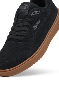 Svart mocka sneakers med en brun gummisula, med en PUMA-logotyp på tungan och sidan, sex ögla och perforerade detaljeringar på tån.