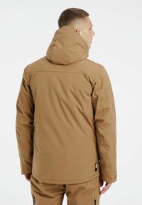Chaqueta aislante marrón con capucha, con una textura suave y un diseño minimalista. Incluye una etiqueta de logo en el dobladillo y costuras limpias.