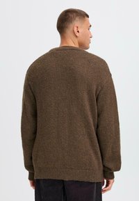 Brown knitted sweater with a loose fit, ribbed cuffs and hem, and a textured finish. Features a round neckline and dropped shoulders.