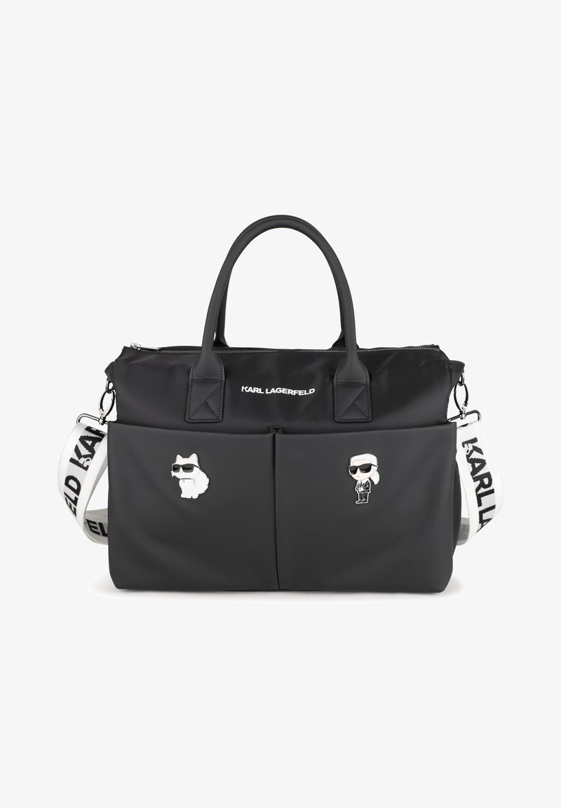 Μαύρη χειραποσκευή νάιλον με διπλές κορυφαίες λαβές, αποσπώμενο ιμάντα, δύο μπροστινές τσέπες και ασημένιο μεταλλικό εξοπλισμό. Διακοσμημένη με καρφίτσες κινούμενων σχεδίων ενός σκύλου και ενός άνδρα.