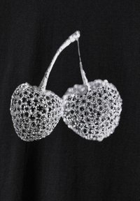 Črna tkanina z grafiko dveh češenj, zasnovana z rešetkastim vzorcem in okrašena s sijočimi detajli.