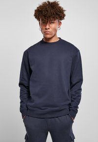 Sudadera azul marino con cuello redondo, mangas largas y puños acanalados. Confeccionada en material suave, presenta un corte relajado con detalles mínimos.