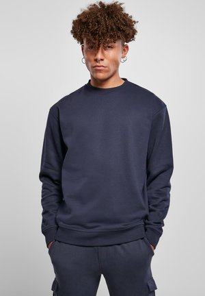 Sudadera azul marino con cuello redondo, mangas largas y puños acanalados. Confeccionada en material suave, presenta un corte relajado con detalles mínimos.