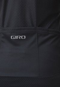 Svart Giro cykeltröja med andningsbar meshstruktur, prickigt mönster och en reflexlogo på nedre delen av ryggen.