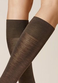 Braune knielange Socken mit einem strukturierten oberen Bündchen und einem glatten Unterteil, die einen Verlauf von dunkleren zu helleren Farbtönen zeigen.