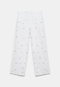 Pantalon blanc à jambes larges avec des embellissements en œillets argentés dispersés et une fermeture éclair à l’avant.