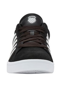 Černé semišové sneakers s bílými pruhy, kulatá špička, hnědá šňůrka, plochá bílá podrážka a kulatý logo na jazyku.