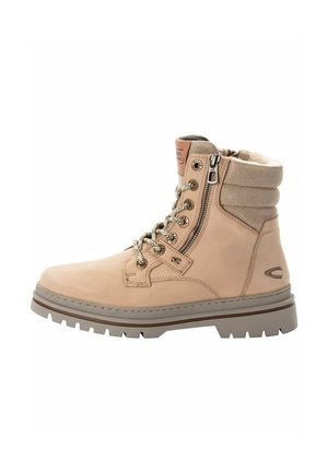Bottine beige en suède avec un laçage sur le devant, fermeture éclair et doublure en fourrure douce. Dispose d'une semelle en caoutchouc texturée et de quincaillerie dorée.