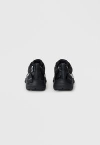 Black athletic shoes with a textured mesh upper, sleek design, padded collar, and logo detail on the heel, featuring pull tabs on the back.