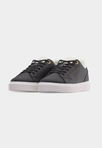 Μαύρα χαμηλά αθλητικά παπούτσια με λευκές σόλες, μαύρα κορδόνια και χρυσά κρικάκια, με το λογότυπο Tommy Hilfiger στο πλάι.