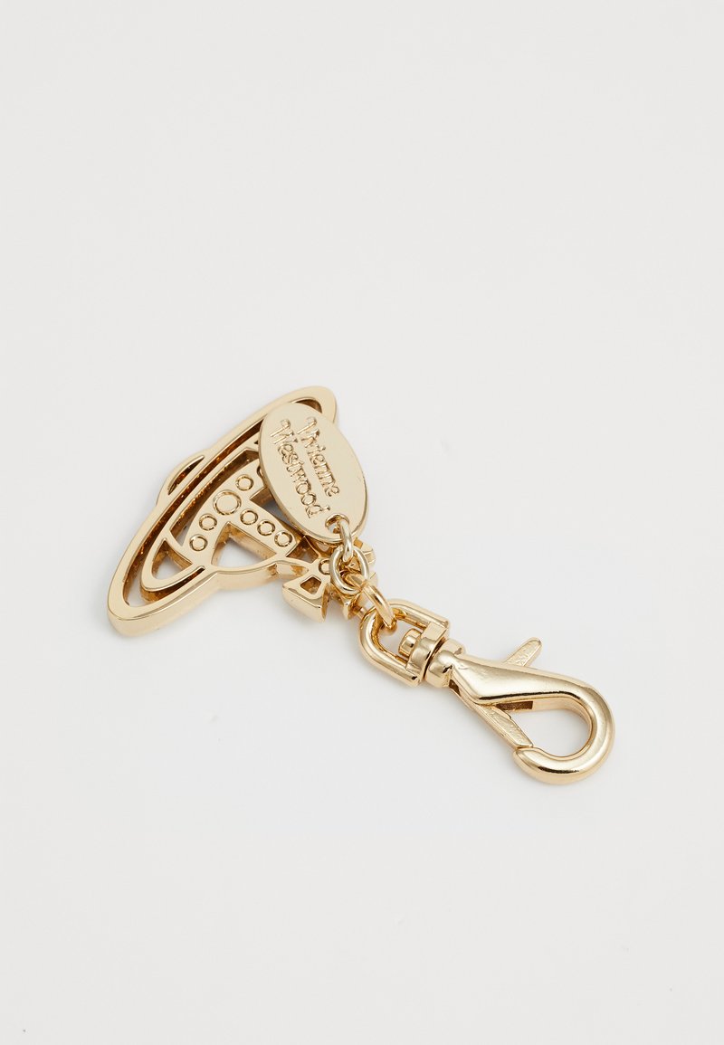 Portachiavi in metallo dorato con un design intricato che ricorda un pianeta con anelli, attaccato a un gancio e a un’etichetta incisa con "Vivienne Westwood."