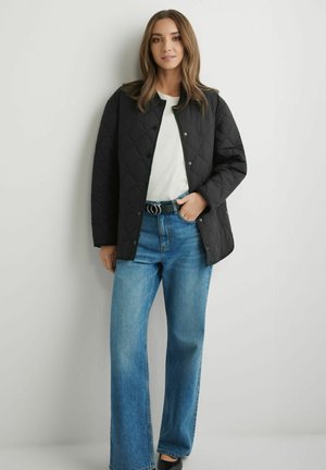 Czarna pikowana kurtka z zatrzaskami, noszona na białej koszuli. Do tego jasnoniebieskie dzwony i czarny pasek z podwójną sprzączką.