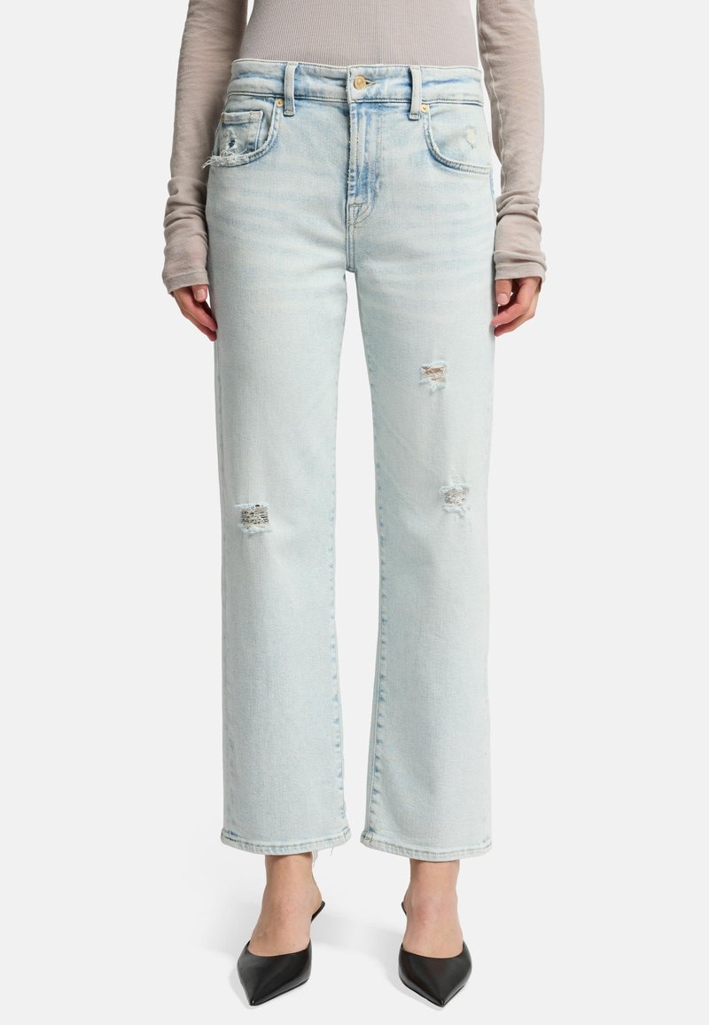 Jeans in denim azzurro chiaro con una vestibilità rilassata e gamba ampia, caratterizzati da toppe strappate e orli sfrangiati. Chiusura con bottone e tasche frontali e posteriori.