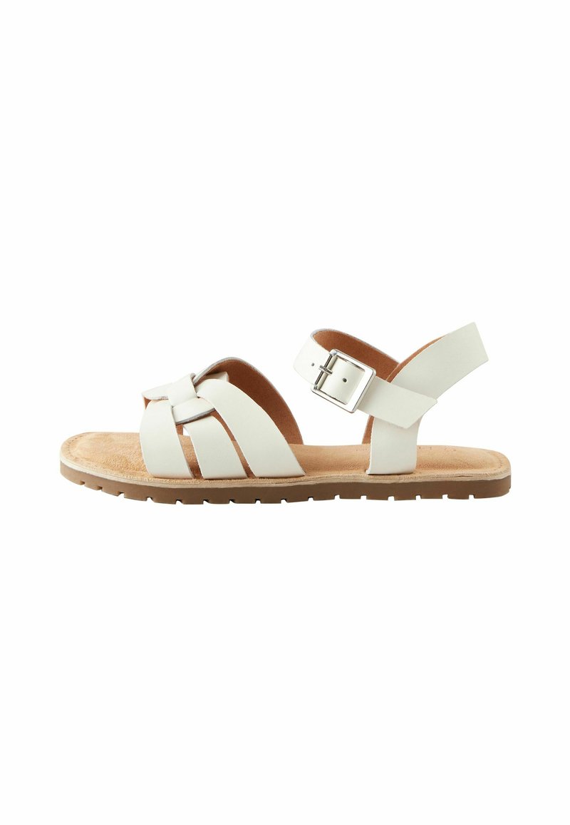 Sandale en cuir blanc avec un design à lanières croisées, une sangle arrière réglable avec boucle, et une semelle rembourrée marron.