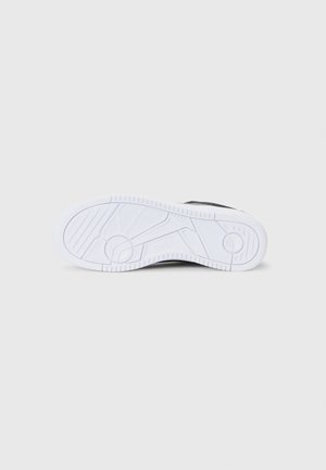 Semelle de sneaker noire avec un fond en caoutchouc blanc, présentant un motif texturé pour l'adhérence et le logo "Polo" affiché sur le côté.