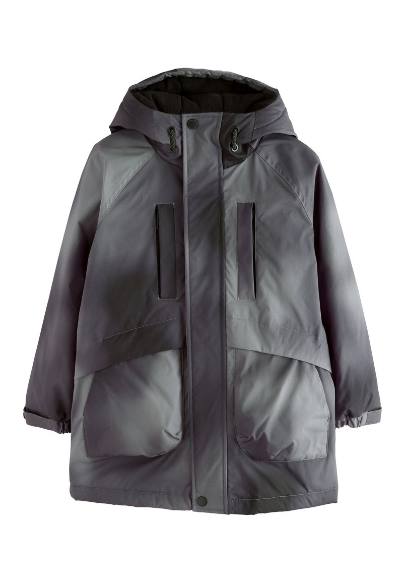 Veste grise imperméable avec capuche, dotée de deux grandes poches avant, de poches poitrine zippées et de cordons de serrage réglables à la capuche et aux poignets.