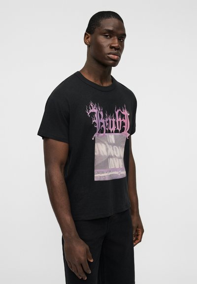 Μαύρο βαμβακερό t-shirt με γραφικό σχέδιο που απεικονίζει ροζ φλόγες και ένα ορθογώνιο κεντρικό μοτίβο. Κοντά μανίκια και χαλαρή εφαρμογή.