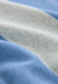 Puuvillane kangas, millel on horisontaalsed triibud hele sinises, tumedas sinises ja hallis. Pehme tekstuur kergelt harjatud pinnaga.