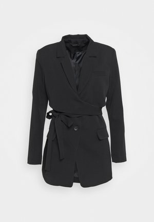 Blazer noir portefeuille en tissu léger. Il présente un col à revers, un bouton unique et une taille nouée pour un ajustement personnalisable. Deux poches à l'avant.