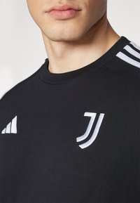Sort kortærmet skjorte lavet af blødt materiale, med hvide Adidas-striber og Juventus-logo broderet på brystet.