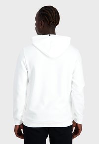Felpa bianca con cappuccio caratterizzata da una texture morbida, maniche lunghe e una zip sul colletto. Il retro presenta un design minimalista.
