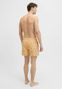 Șorturi de baie pentru bărbați, de culoare portocalie, cu dungi albastre și modele mici. Talie elastică cu șnur, material ușor, croială până la genunchi.