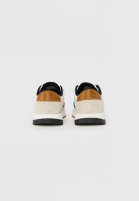 Adidași albi și crem cu accente negre. Detalii din suede la călcâi în nuanța tan. Talpă intermediară groasă albă și talpă exterioară durabilă neagră. Branding Calvin Klein vizibil.