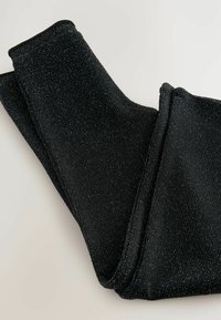 Black ribbed fabric leggings with metallic shimmer, featuring a smooth texture and elastic waistband, folded neatly on a light background.