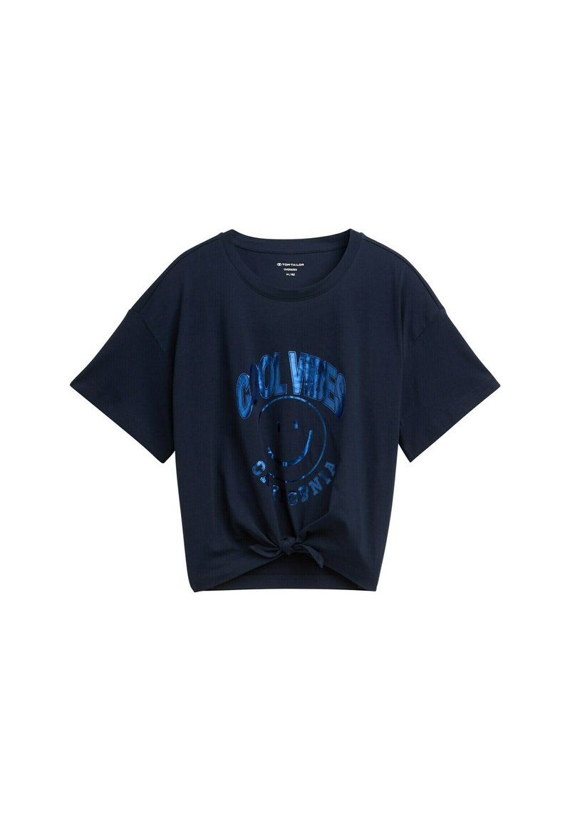 Camiseta de manga corta azul marino con detalle de nudo en el frente. Presenta una impresión gráfica que dice "BUENAS VIBRAS CALIFORNIA" en letras reflectantes azules.